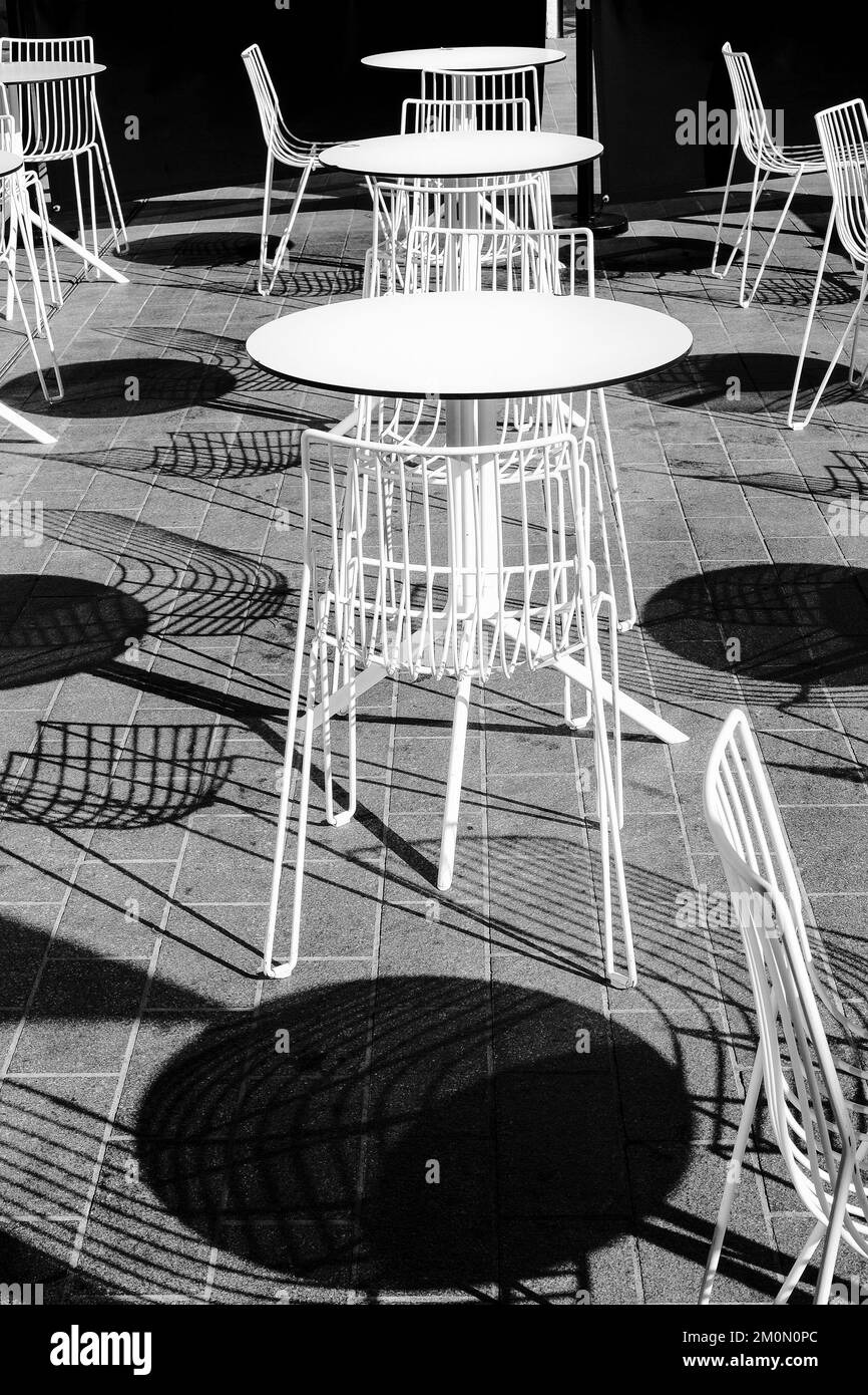 Kontrastreiches Schwarzweißbild mit runden Tischen und Schatten im Café. Stockfoto