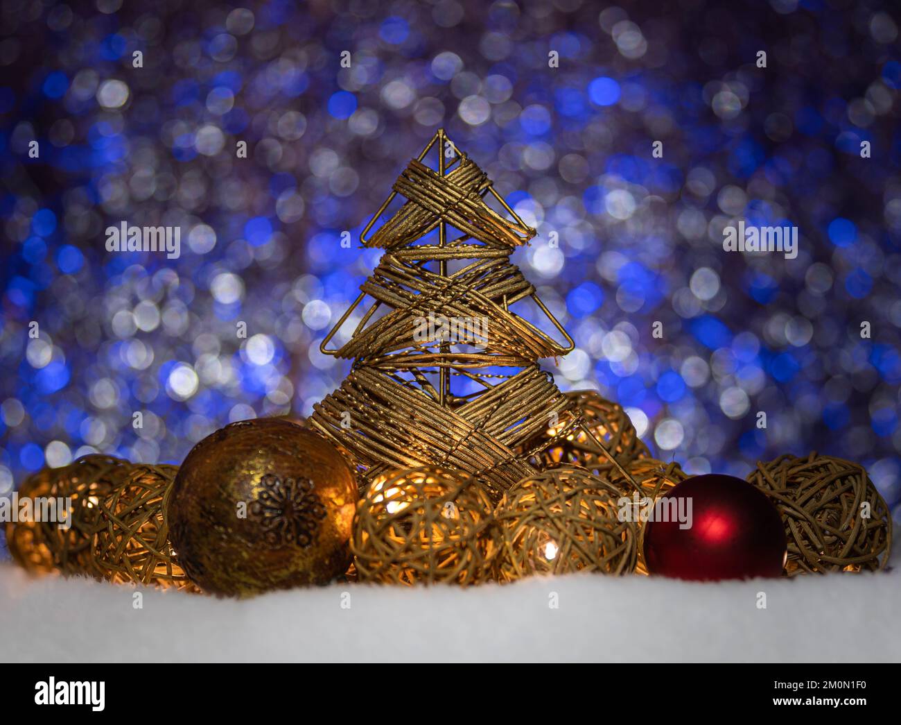 Weihnachtsbaumschmuck, Kugeln und Rattankugeln leuchten auf glänzendem, bunten Hintergrund. Stockfoto