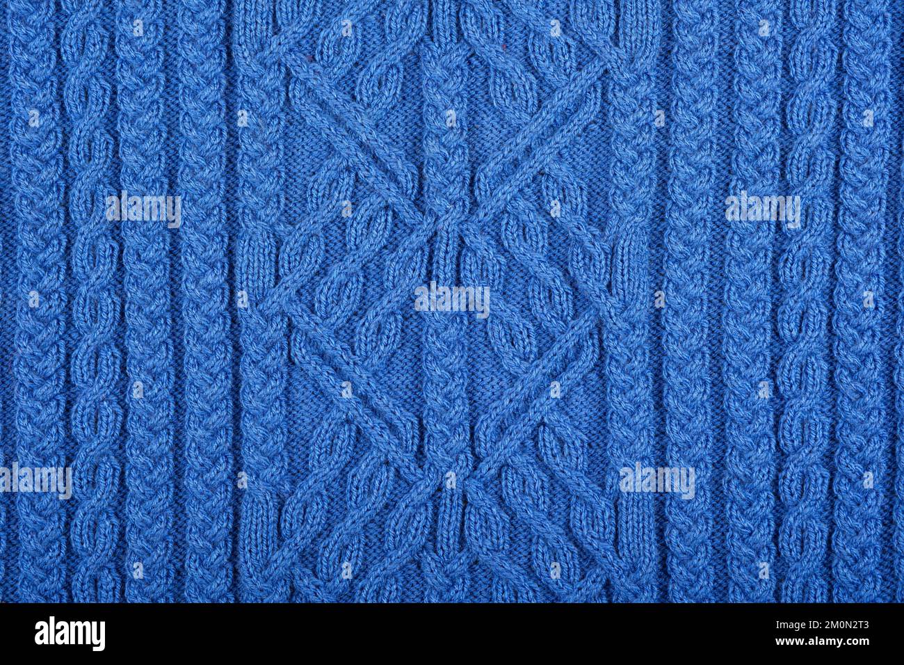 Gestrickter blauer Hintergrund. Großer Strickstoff mit Muster. Nahaufnahme einer Strickdecke. Stockfoto