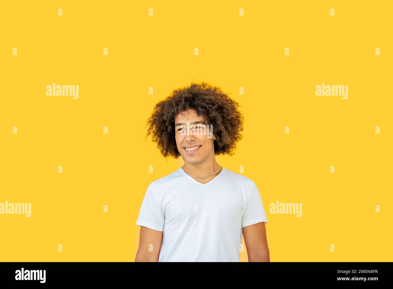 Porträt eines lächelnden jungen afro-italienischen Teenagers mit dickem lockigem Haar auf gelbem Hintergrund. Glückliche, multiethnische junge Männer. Absolut Stockfoto