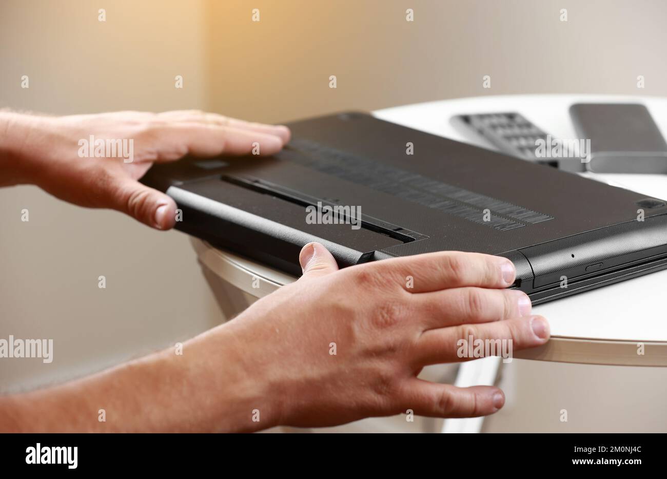 Die Hände des Reparaturmanns, der den Akku aus dem Laptop entfernt ...