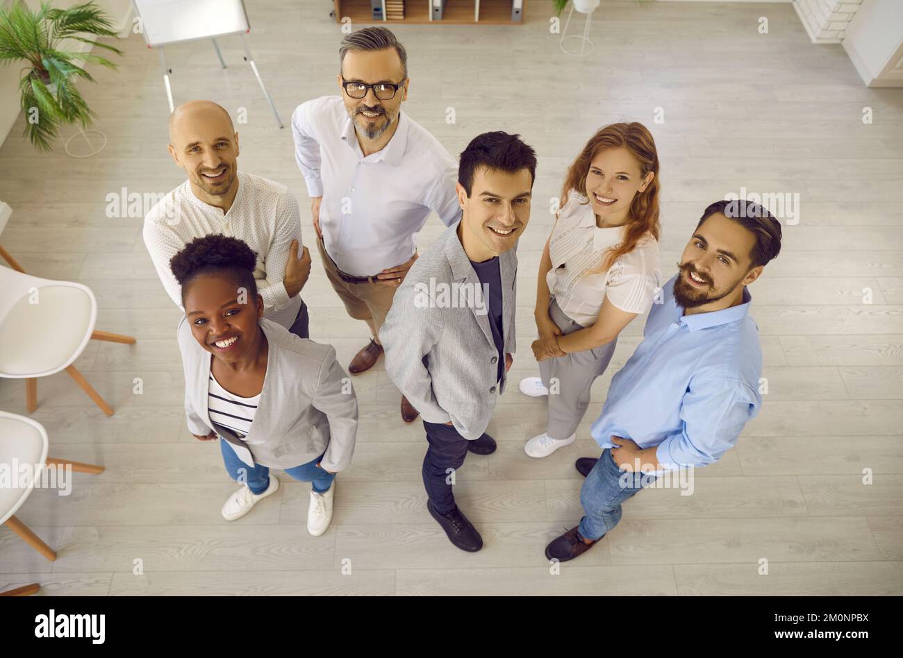 Ein Team glücklicher, multiethnischer Geschäftskollegen, die gemeinsam lächeln und im Büro nach oben schauen. Stockfoto