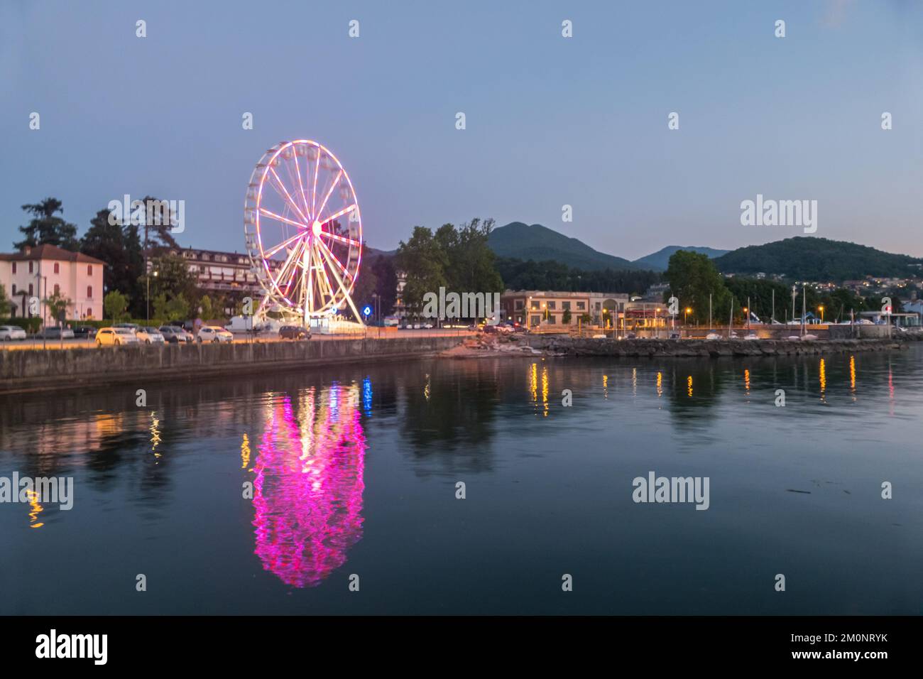 Luino, Italien: 05-18-2021: Riesenrad beleuchtet am Abend mit Lichtern, die auf dem Lago Maggiore in Luino reflektieren Stockfoto