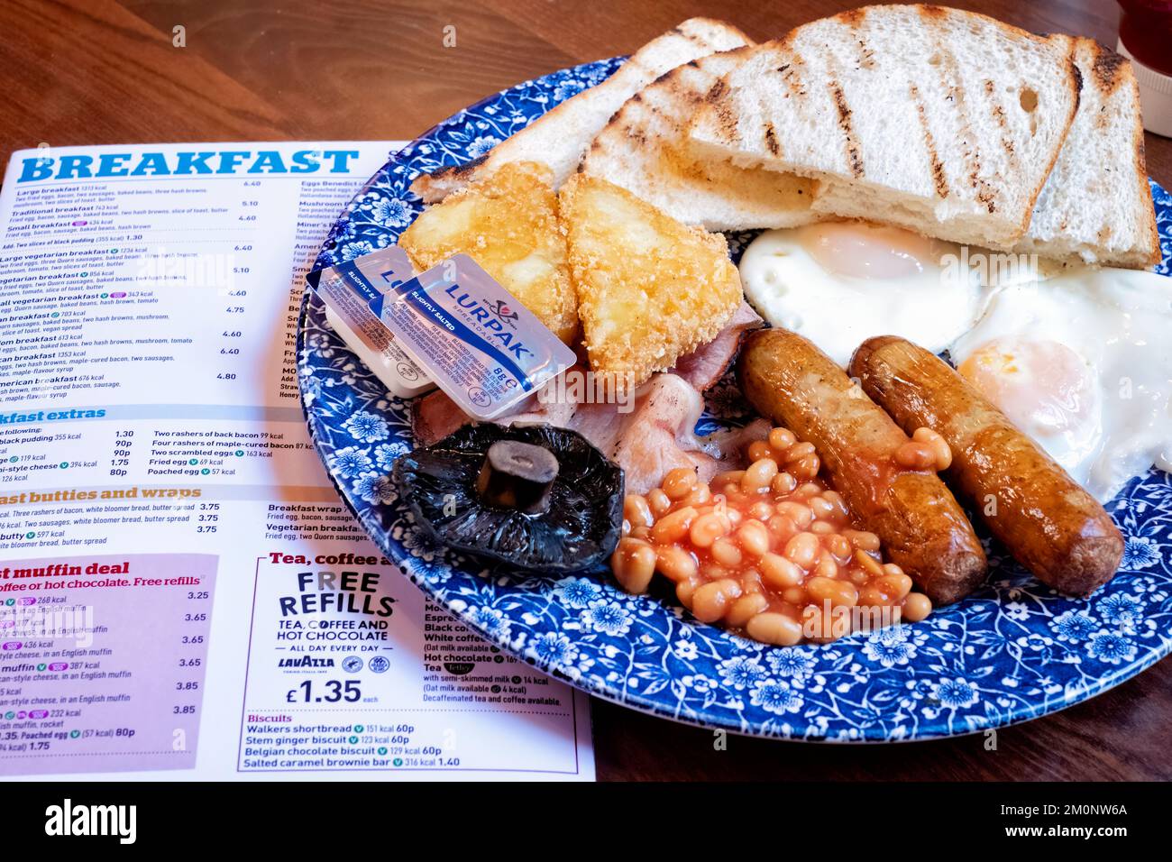 Ein Wetherspoons großes Frühstück, serviert in einem Wetherspoons Pub. Das Frühstück kostet 1406 Kalorien. Die Karte für das Frühstücksmenü im Pub befindet sich an der Seite des Tellers Stockfoto