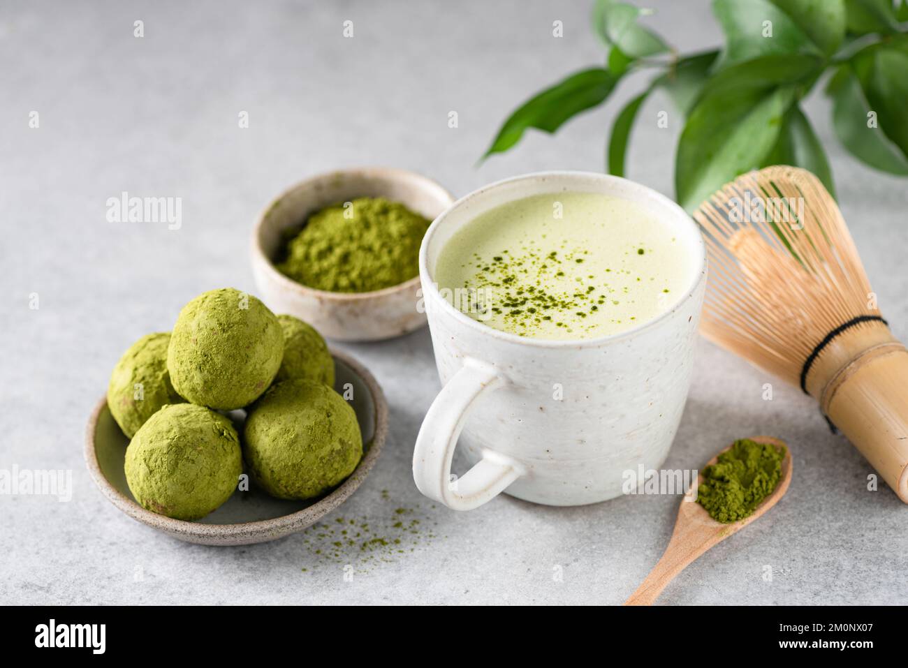 Grüner Tee Matcha Latte im Becher serviert mit veganen Matcha Trüffeln Stockfoto