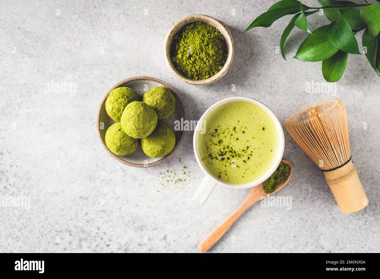 Grüner Tee Matcha latta und Matcha Trüffel auf grauem Steinhintergrund, Draufsicht. Gesunde vegane Energienahrung Stockfoto