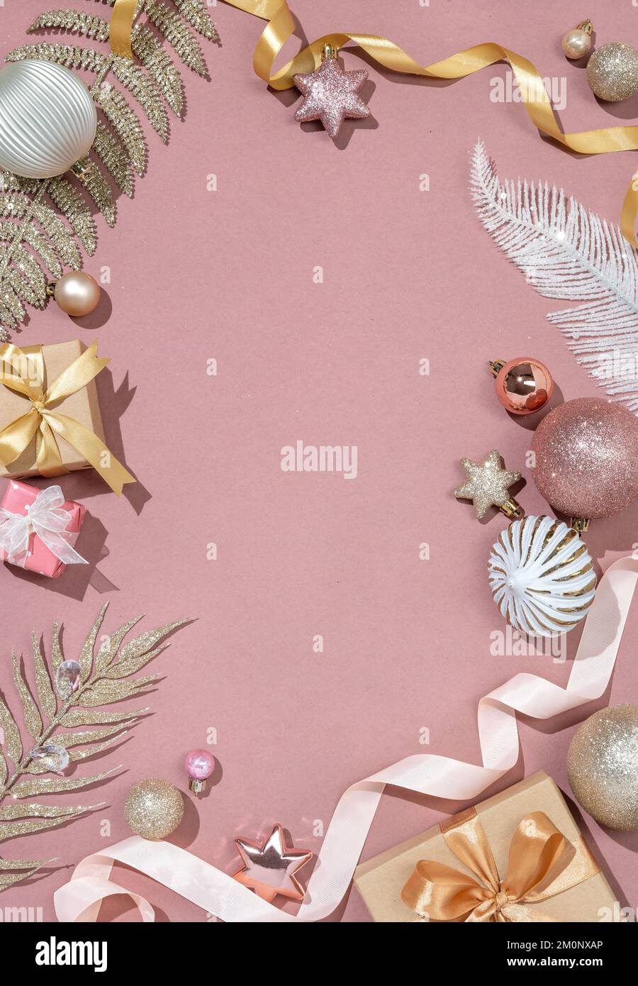 Weihnachtlicher Hintergrund mit glänzenden Zweigen, Dekorationsspielzeug und Geschenkkästen auf pinkfarbenem Hintergrund. Merry Christmas und Happy New Year Concept. Speicherplatz kopieren. Stockfoto