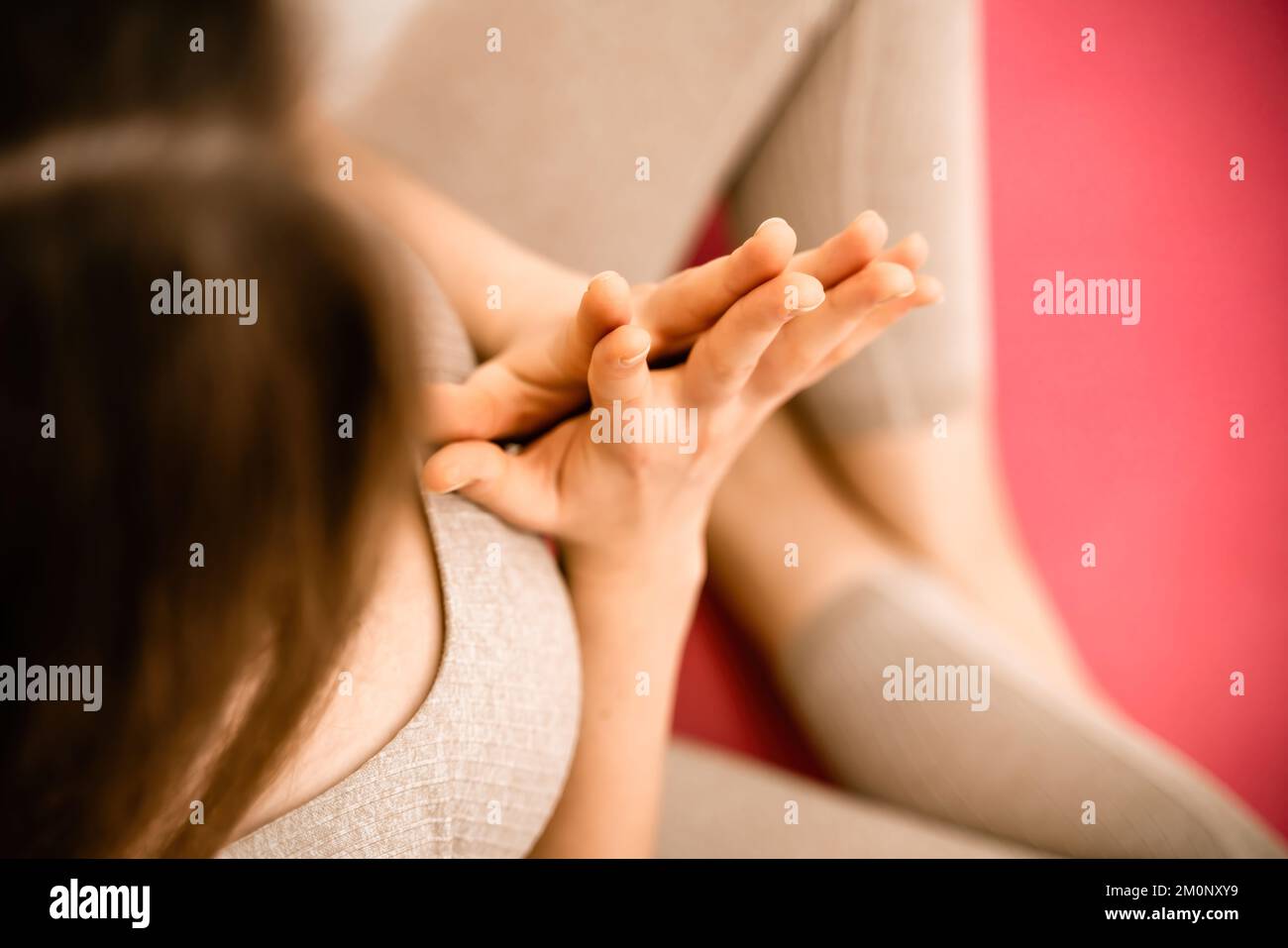 Mädchen macht Yoga. Junge Frau praktiziert Asanas mit beigefarbenem 1-Tonne-Hintergrund. Stockfoto