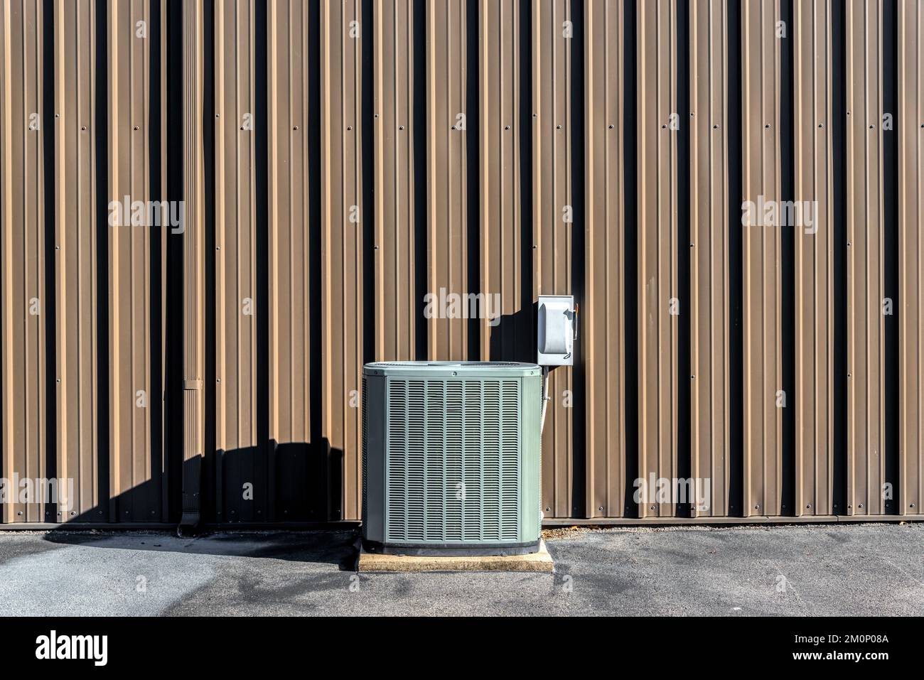 Ein horizontales Bild eines Klimaanlagenkompressors vor einer leeren braunen Wand mit Platz zum Kopieren. Stockfoto