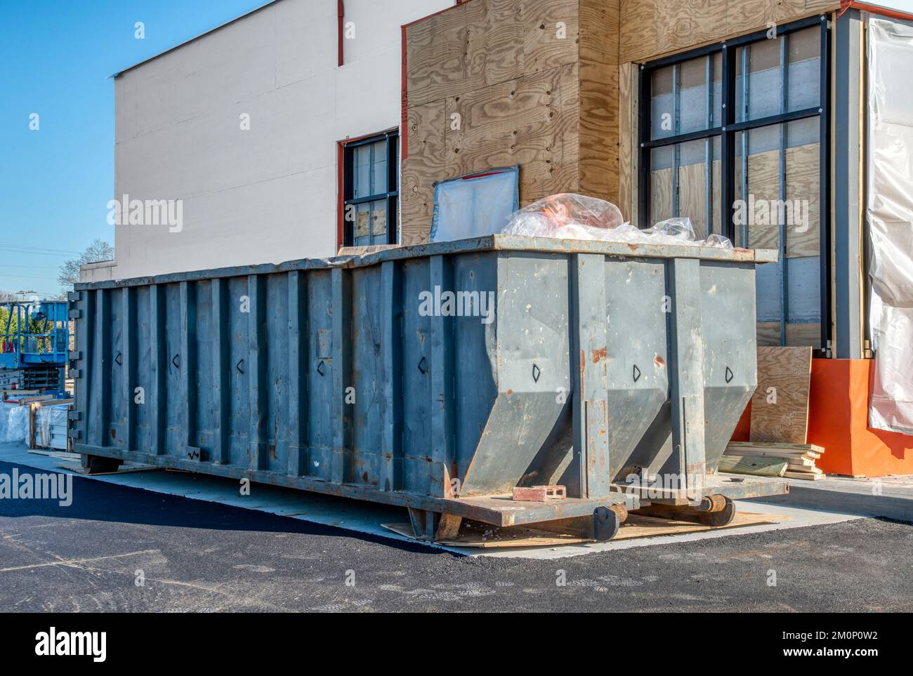 Ein großer, schwerer Müllcontainer neben einem neuen Fast-Food-Restaurant im Bau. Stockfoto