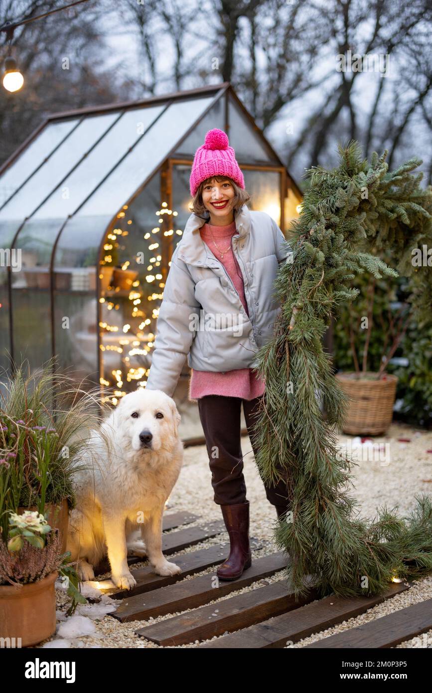 Eine Frau mit einem Hund in einem wunderschön dekorierten Hinterhof für einen Winterurlaub Stockfoto