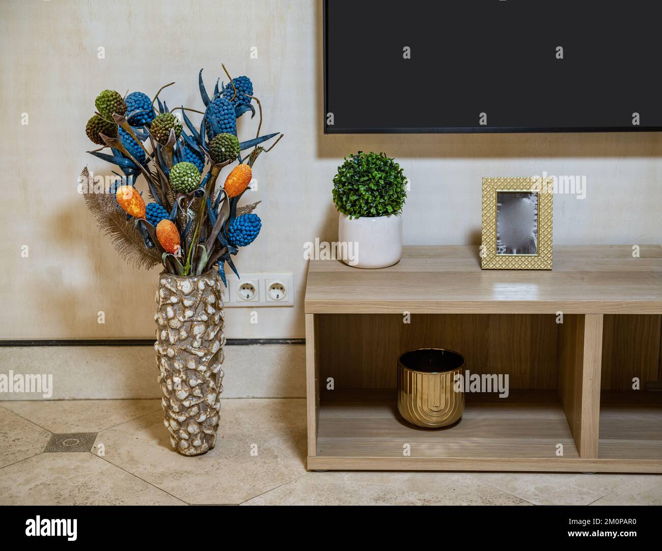 Innenraum. Dekorative Vase. TV-Standfuß aus Holz. Grüne Blume. Bilderrahmen. Stockfoto