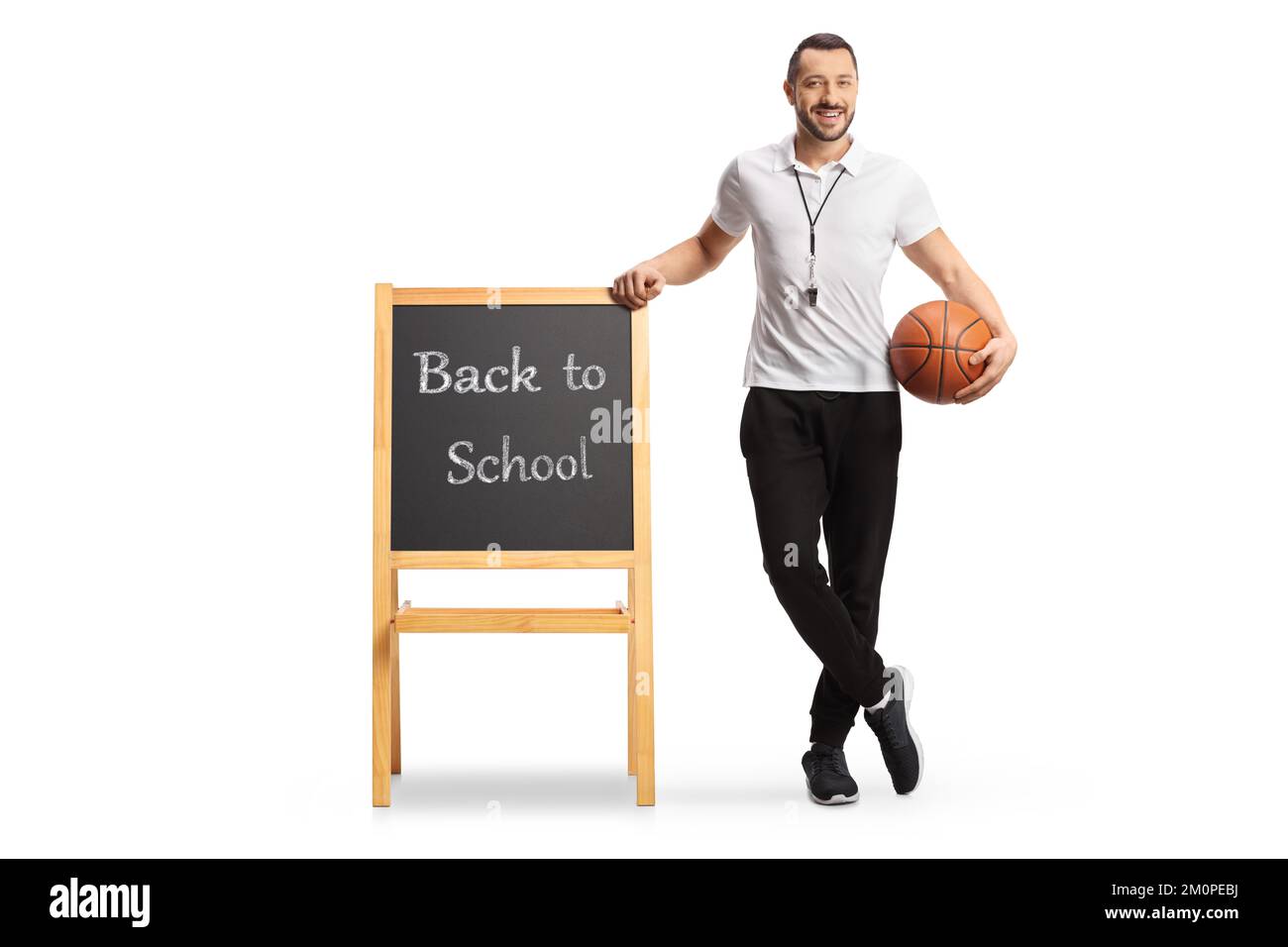 Sportlehrer hält einen Basketball und lehnt sich an eine Tafel mit Text zurück zur Schule isoliert auf weißem Hintergrund Stockfoto
