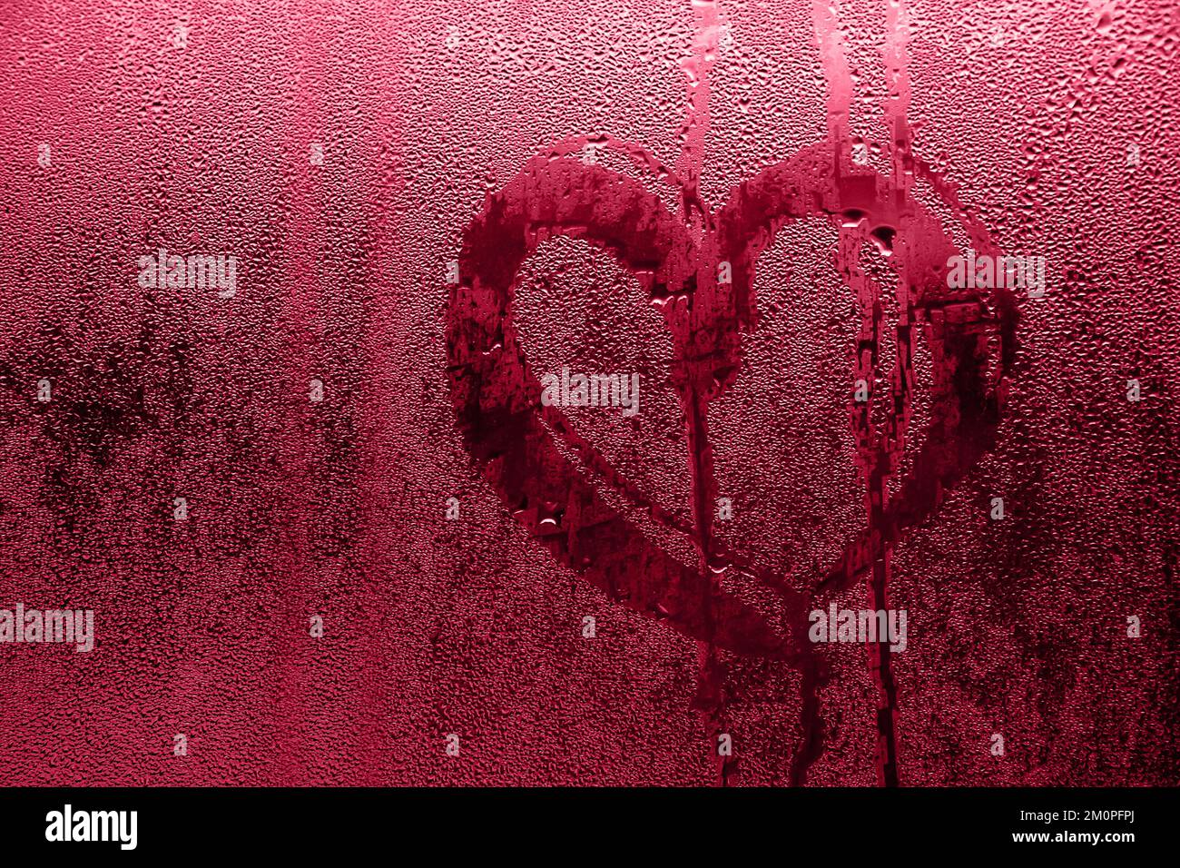 Das Herz ist auf beschlagenes Glas gemalt. Valentinstag, Liebessymbol auf gefrorenem Glas im Winter. Selektiver Fokus. Farbe des Jahres 2023 - Viva Magenta Stockfoto