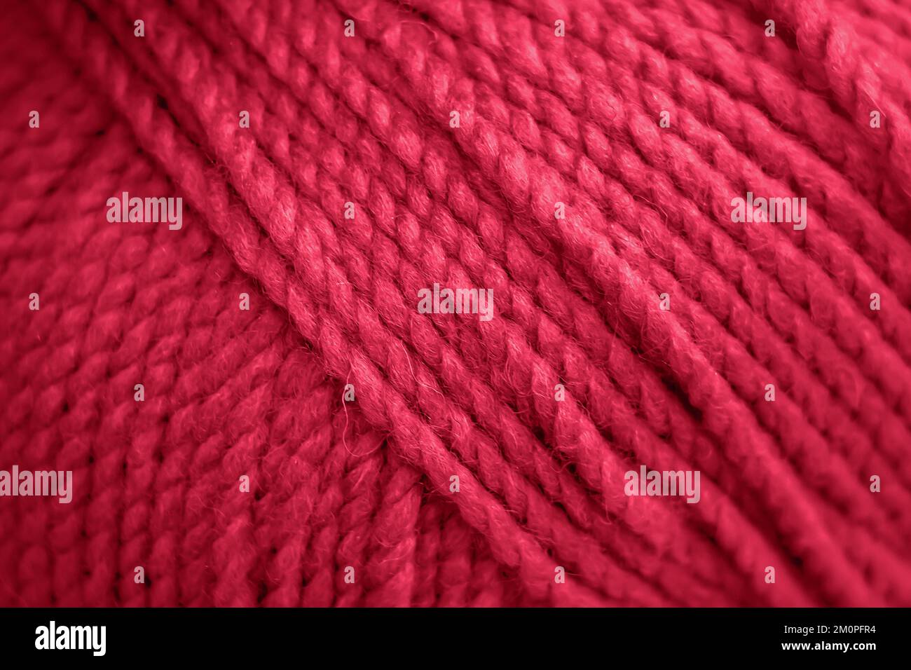 Konsistenz von rosa flauschigen Wollfäden zum Stricken von Nahtaufnahmen. Farbe des Jahres 2023 - Viva Magenta Stockfoto