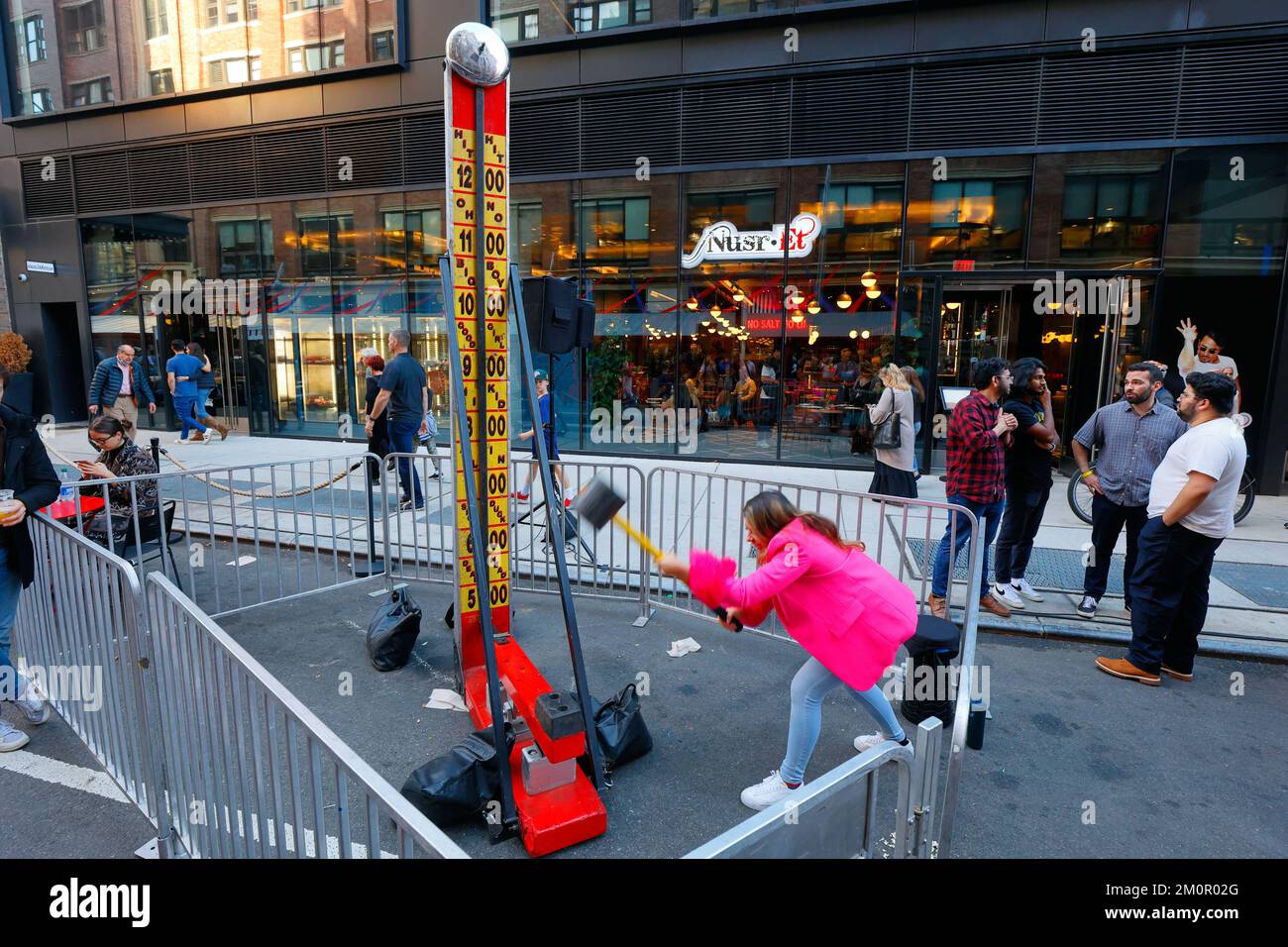Eine Frau spielt Hi Striker, ein Karnevalsspiel mit einem Vorschlaghammer, auf der Chelsea Market 25. Anniversary Street Fair, New York. Stockfoto