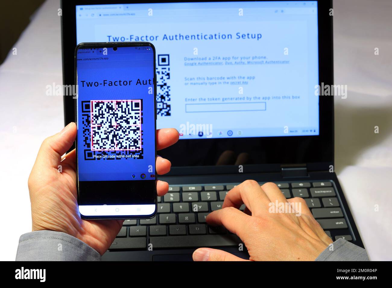 Eine Person scannt einen QR-Code mit der Google Authenticator App auf ihrem Smartphone, um eine zwei-Faktor-Authentifizierung 2FA für sichere Anmeldungen einzurichten Stockfoto