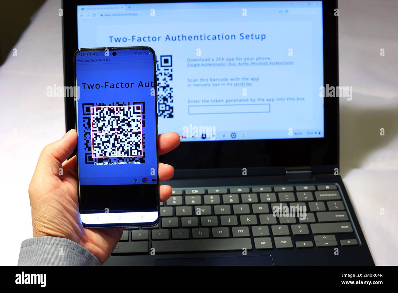 Eine Person scannt einen QR-Code mit der Google Authenticator App auf ihrem Smartphone, um eine zwei-Faktor-Authentifizierung 2FA für sichere Anmeldungen einzurichten Stockfoto