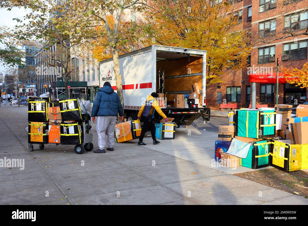 Amazon-Pakete auf der letzten Meile sortieren auf einem Bürgersteig in New York City. Merchants Fleet ist ein Flottenmanagementunternehmen. Stockfoto