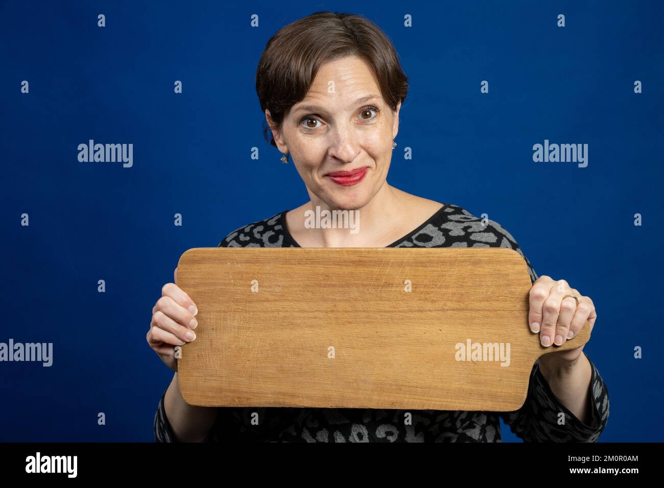 Glückliche ältere Frau, die ein Schneidbrett als Zeichen hält Stockfoto