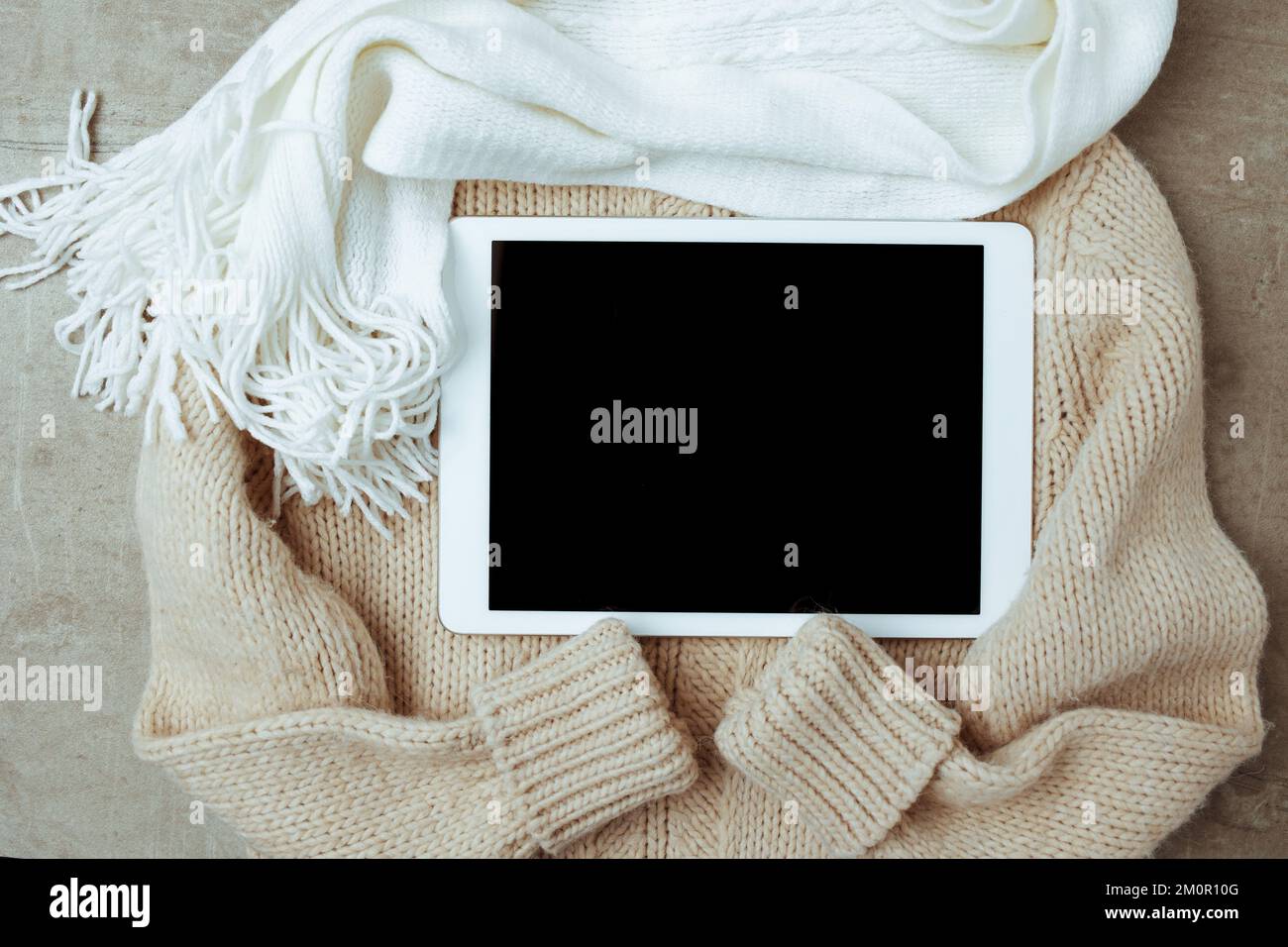 Winterdecke mit Pullover, Schal und Tablet-PC. Stockfoto