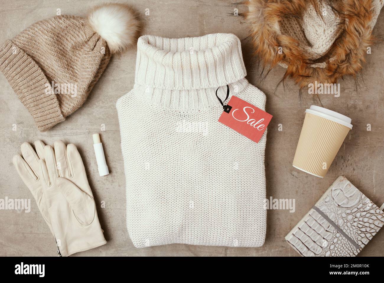 Winterdecke mit Mütze, Schal, Handschuhen, Kaffeetasse, Verkaufsanhänger und Pullover. Stockfoto