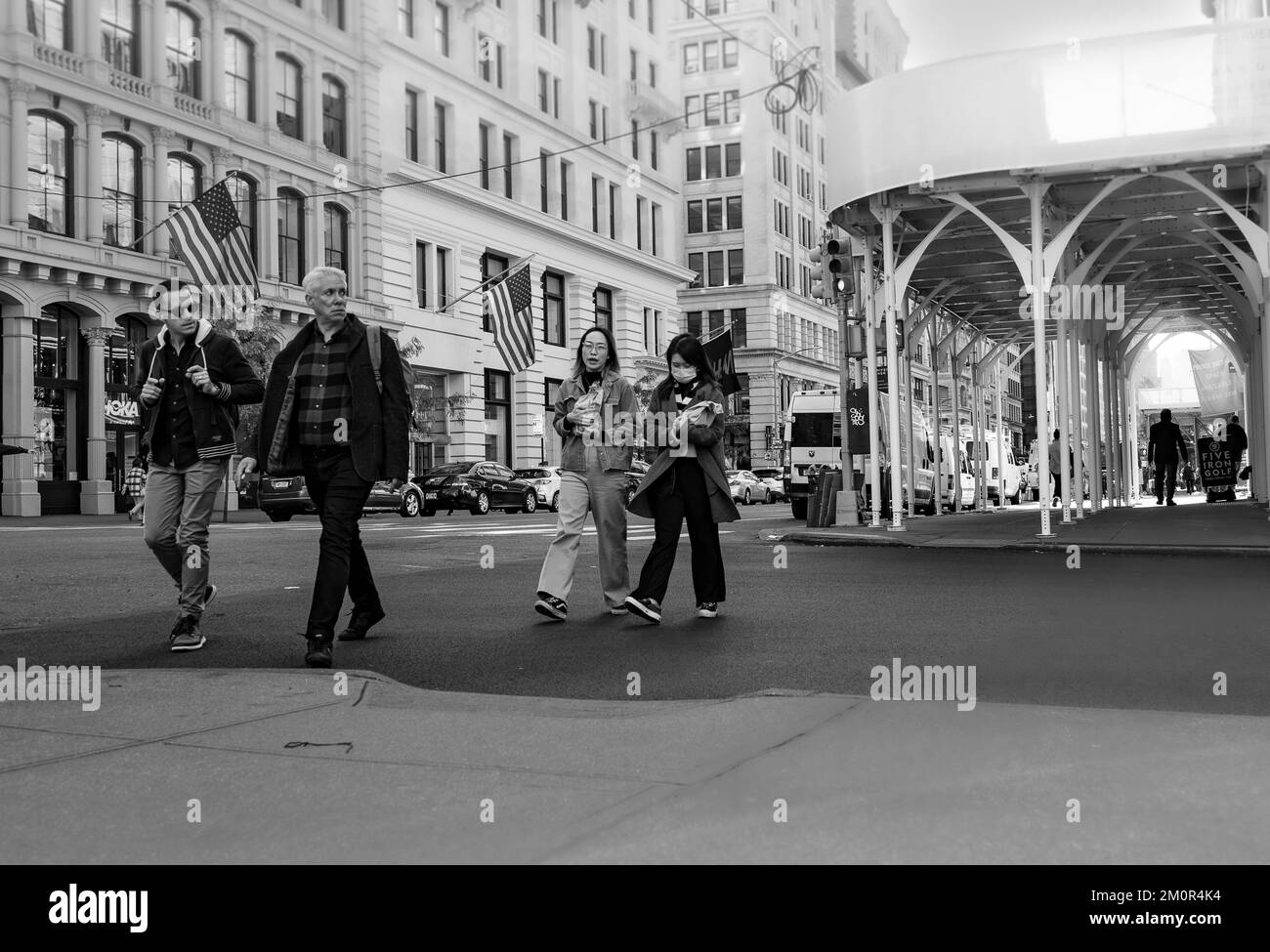 Geschäftsleute und asiatische Frauen überqueren die Straße in New York City - Schwarz-Weiß-Straßenfotografie, Manhattan, USA. Stockfoto