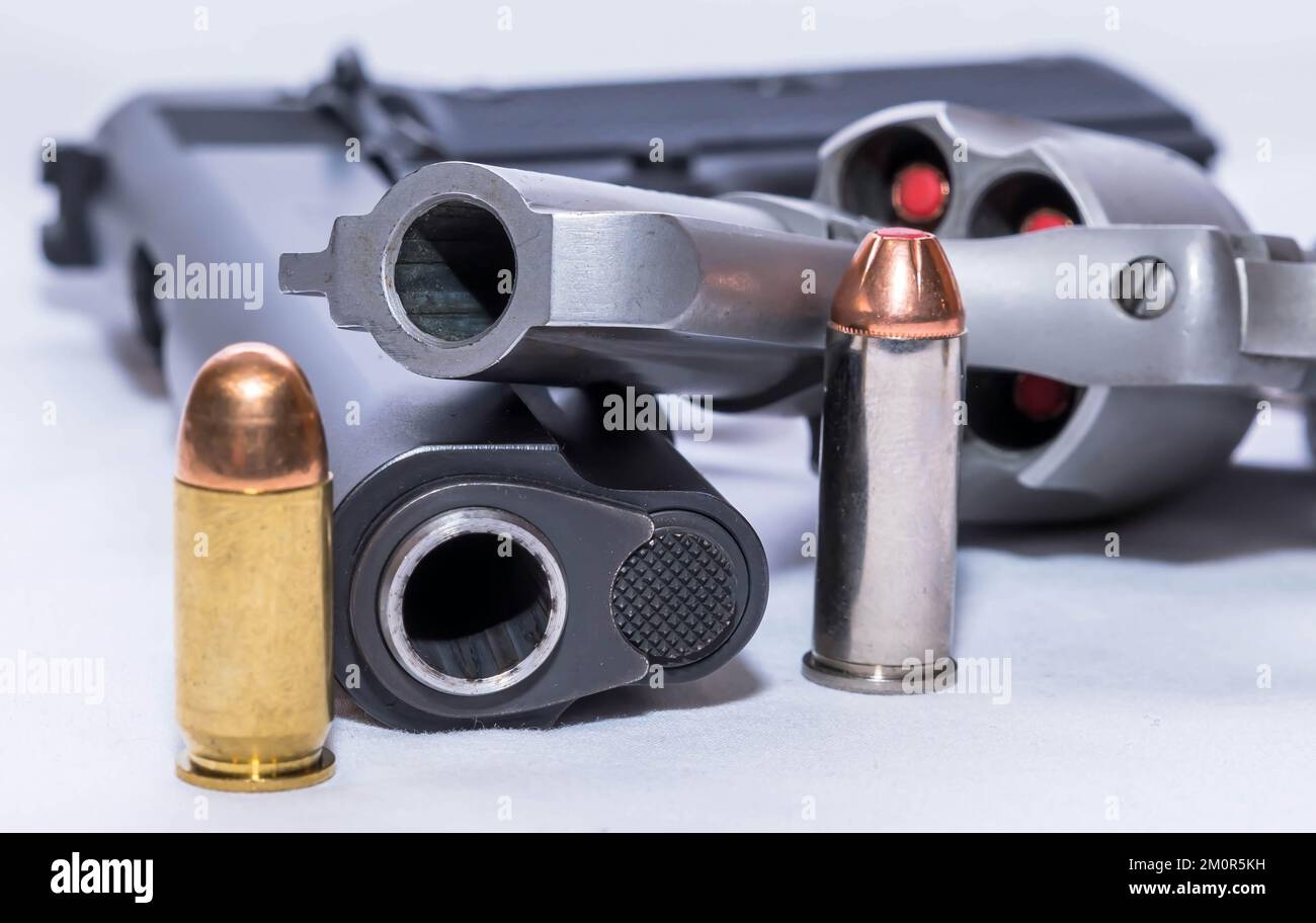 Zwei Handfeuerwaffen, eine Kaliber-45-Pistole und ein 44-Spezialrevolver mit einer Kugel für jede daneben auf weißem Hintergrund Stockfoto