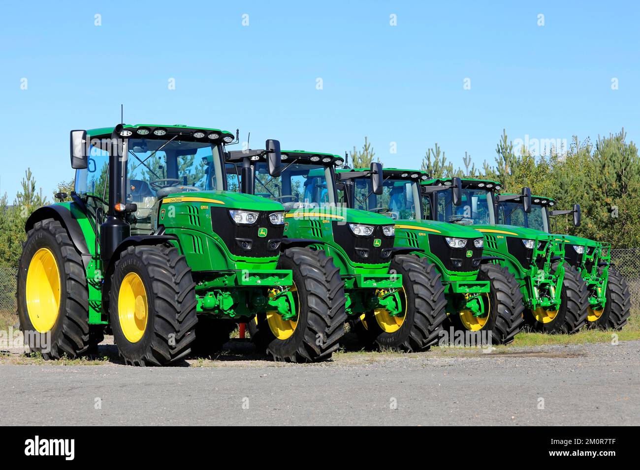 Eine Reihe von fünf neuen John Deere 6155R-Traktoren, die an einem sonnigen Tag im Frühherbst auf einem Hof geparkt wurden. Lieto, Finnland. 22. September 2022. Stockfoto