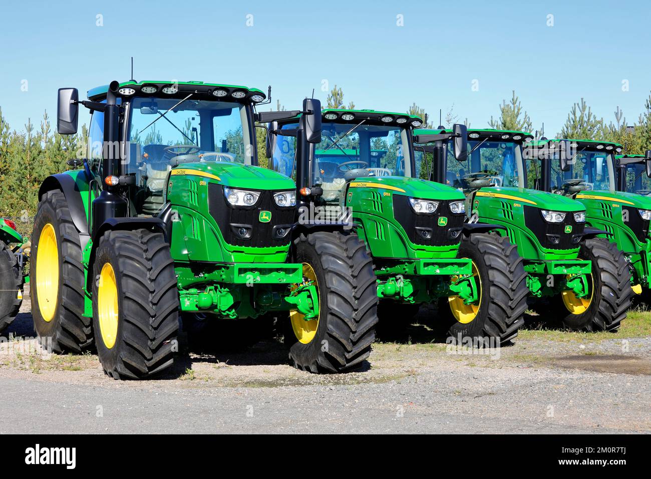Neue John Deere 6155R-Traktoren, die an einem sonnigen Tag im Frühherbst auf einem Hof geparkt wurden. Lieto, Finnland. 22. September 2022. Stockfoto