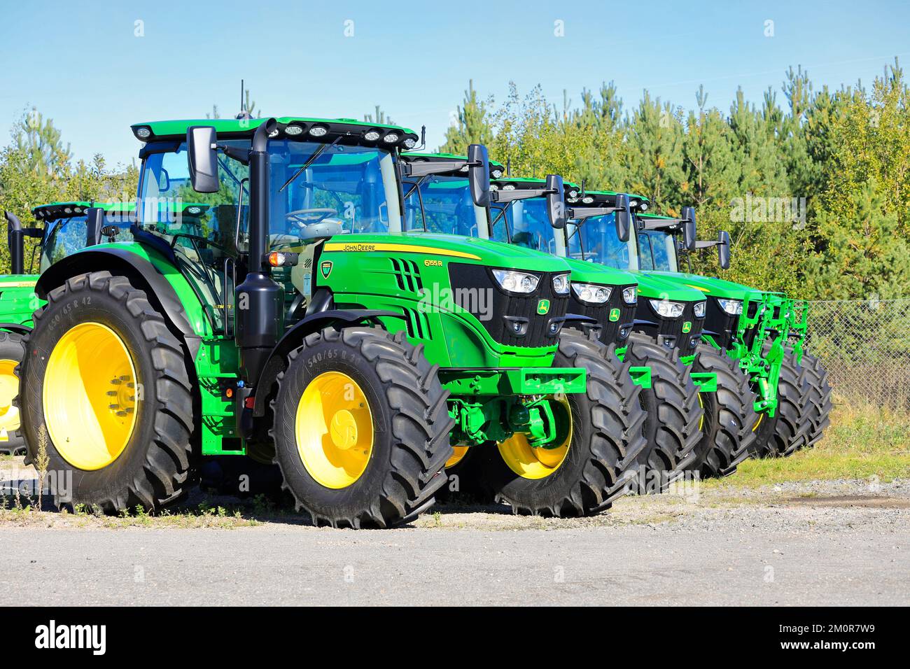 Die neuen John Deere 6155R-Traktoren stehen an einem sonnigen Tag im Frühherbst auf einem Hof in Folge. Lieto, Finnland. 22. September 2022. Stockfoto