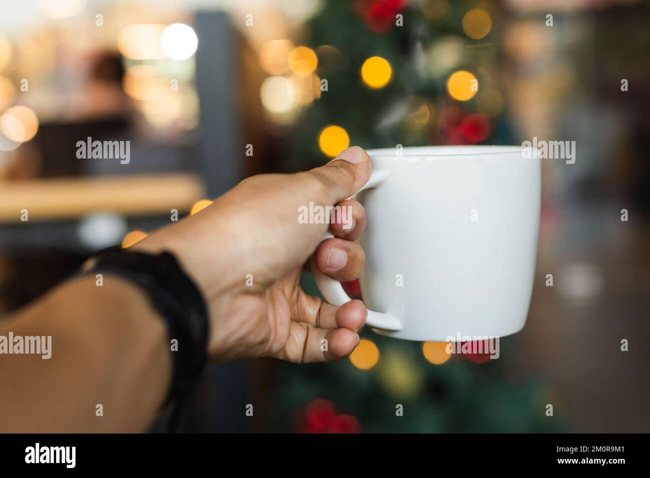 Halten Sie eine Tasse Kaffee mit Bokeh-Licht in der Hand. Stockfoto
