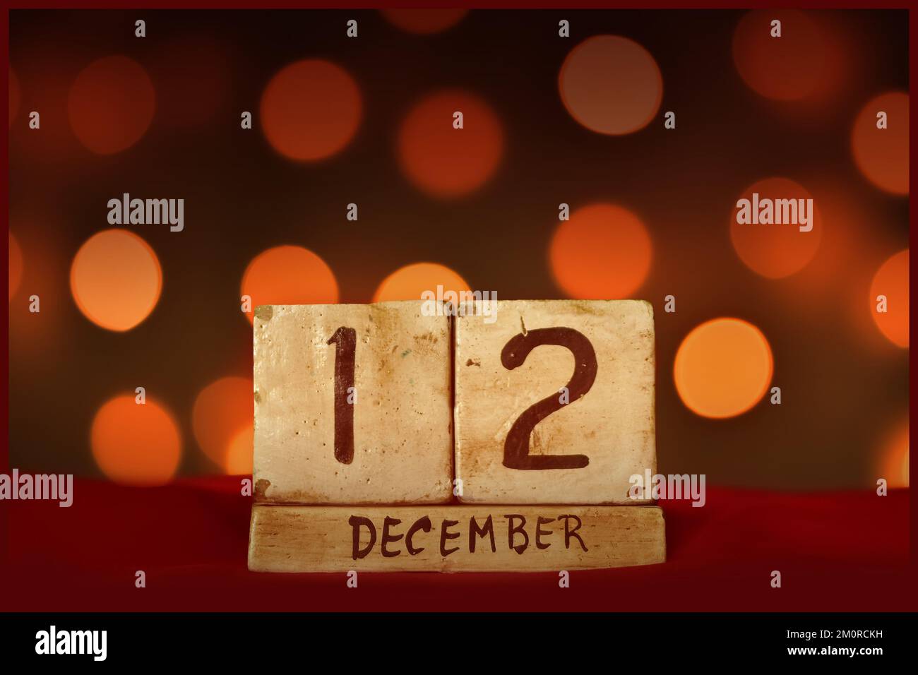 Dezember 12 Vintage Holzblock Kalender auf rotem Stoff, festliche Bokeh Lichter Hintergrund Grußkarte Feiertage, Geburtstag, Datum speichern Stockfoto