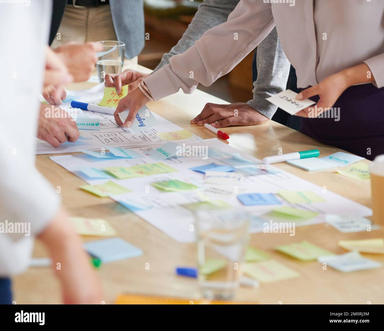 Personen mit unterschiedlichen ethnischen Zugehörigkeiten in Brainstorming-Sitzungen mit Notizen auf dem Schreibtisch. Brainstorming-Sitzung mit Notizen auf dem Schreibtisch. Stockfoto