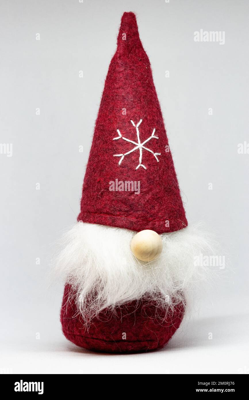 Lustiger süßer Weihnachtszwerg in Rot mit einer Schneeflocke auf der Mütze Stockfoto