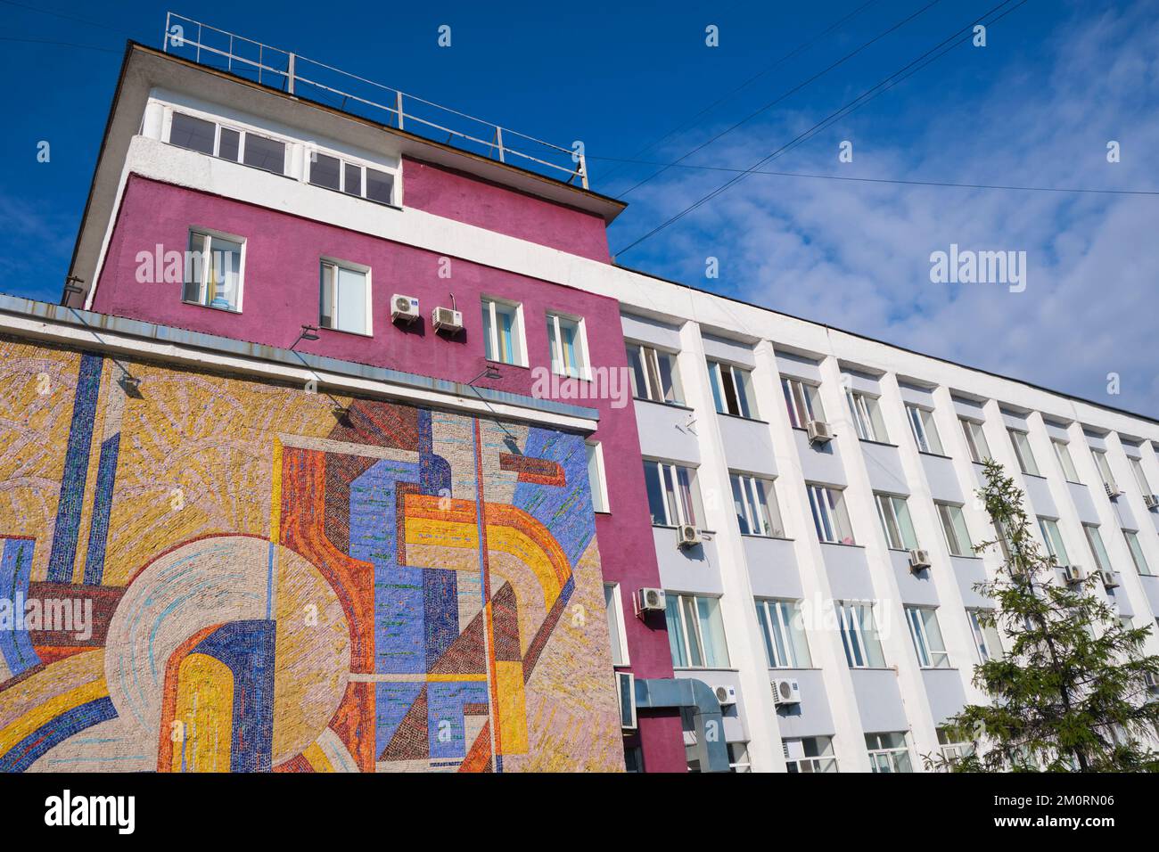 Ein zentrales sowjetisches, russisches, kommunistisches Gebäude mit einem großen Fliesen- und Mosaikgemälde in farbenfrohem, abstraktem Design. In Karaganda, Kasachstan. Stockfoto
