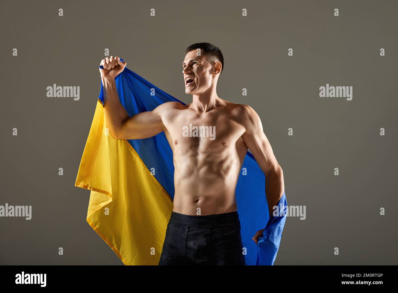 Porträt eines jungen Sportlers, der mit der ukrainischen Flagge auf den Schultern steht und die Emotionen der Sieger ausdrückt. Sieg, Erfolg, Sport, Erfolge Stockfoto