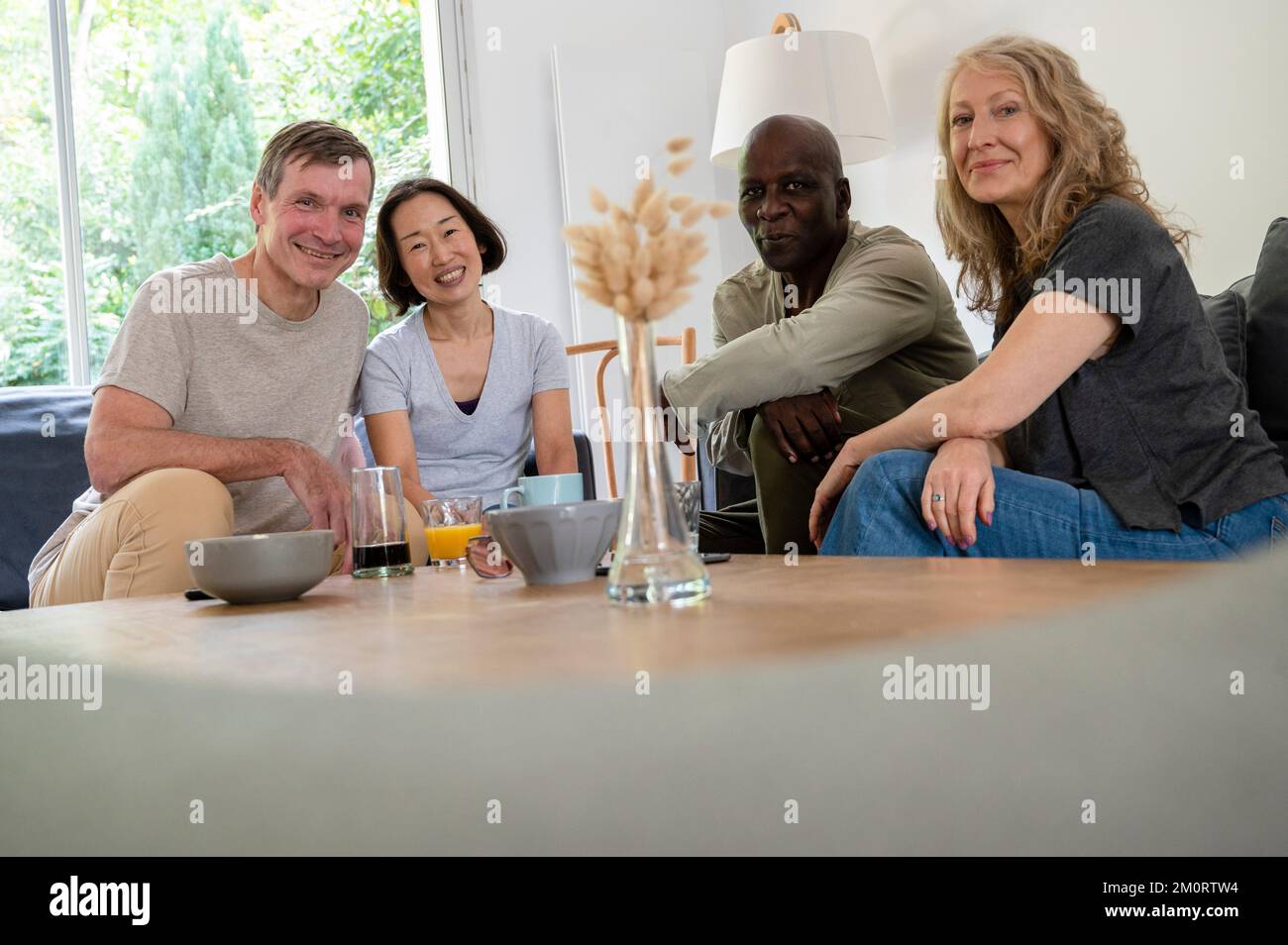 Porträt einer Gruppe von Seniorfreunden, die sich zu Hause amüsieren und die Kamera betrachten Stockfoto