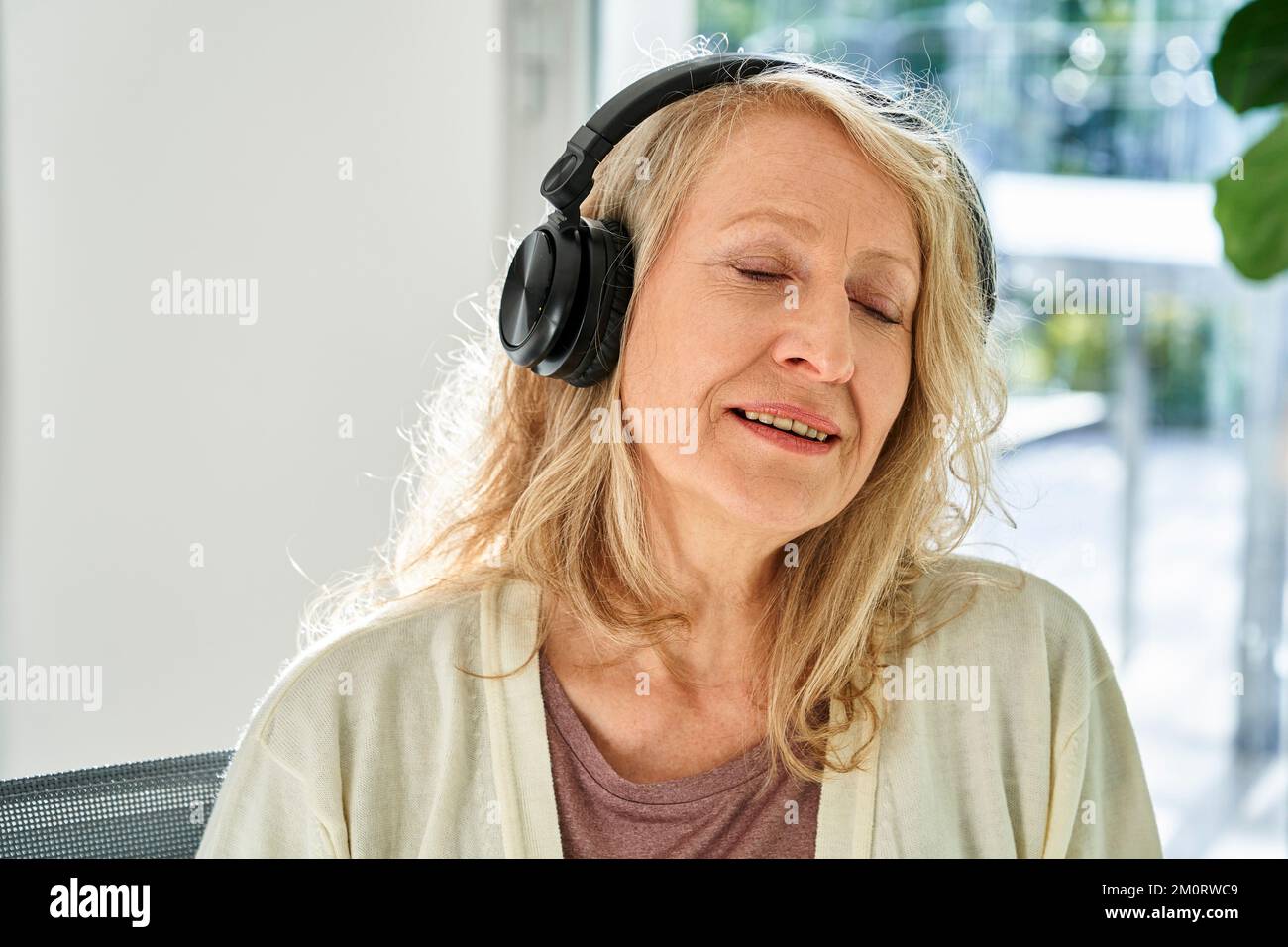 Ältere Frau, die Musik über Kopfhörer hört Stockfoto