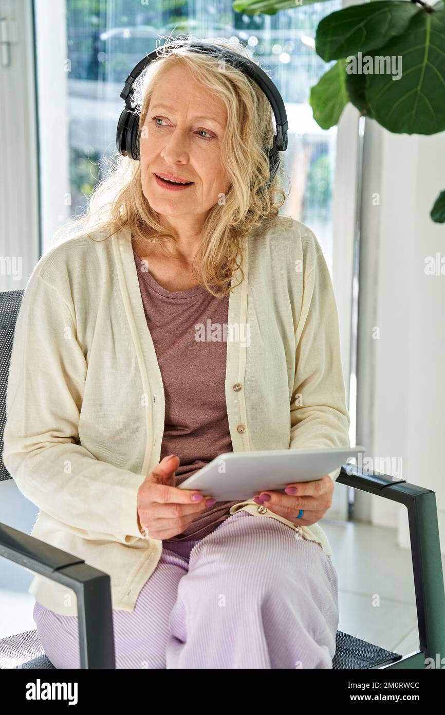 Senior woman listening to music while using digital tablet Stockfoto