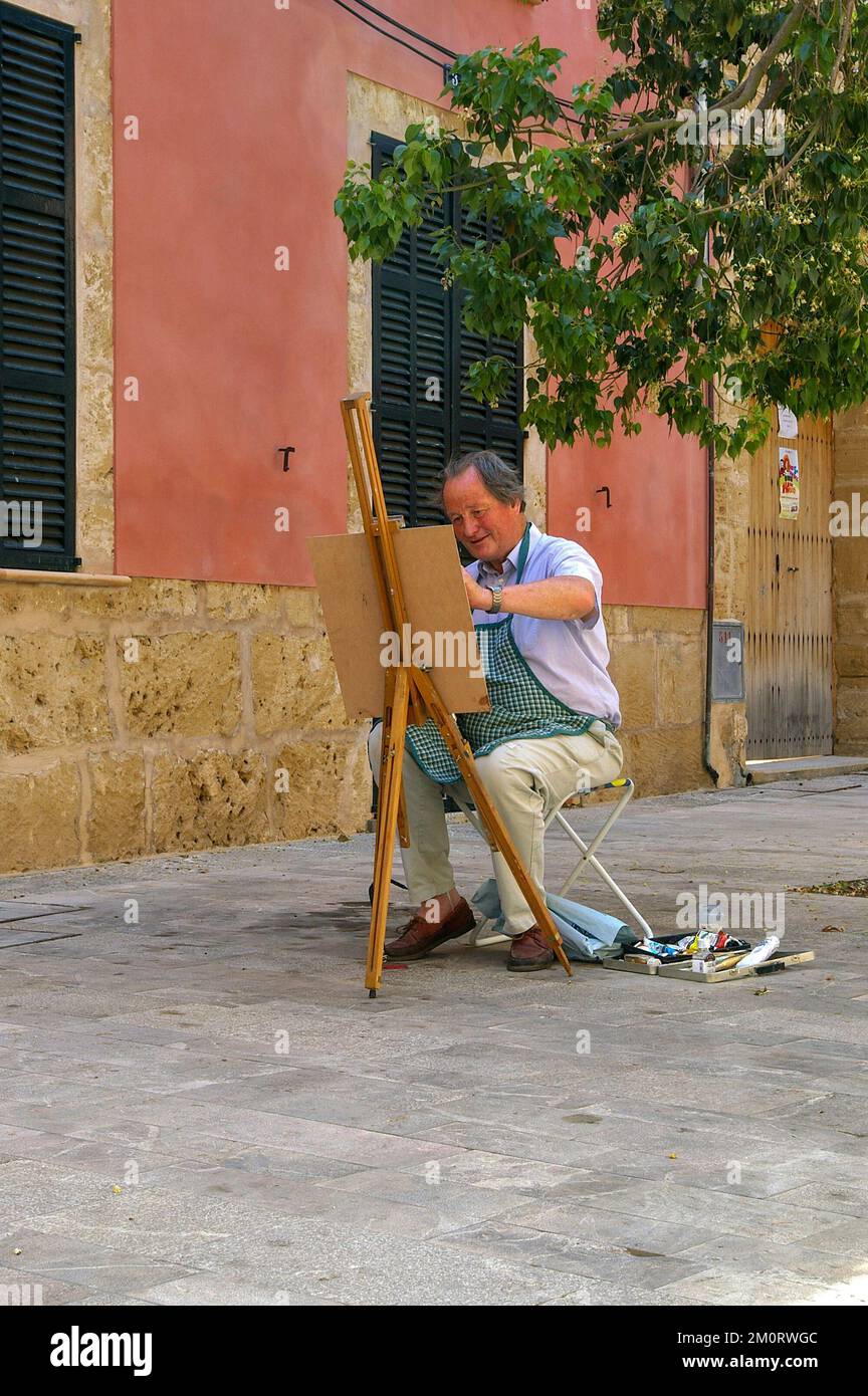 Künstler an seiner Staffelei malt im Sommer eine Straßenszene in der Altstadt von Alcudia, Mallorca, Spanien Stockfoto