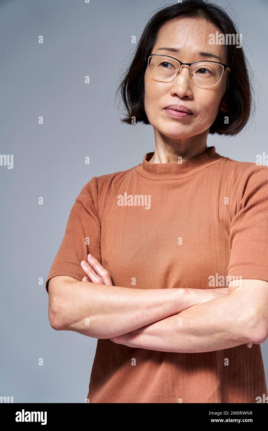 Reife asiatische Amerikanerin mit gekreuzten Armen Stockfoto