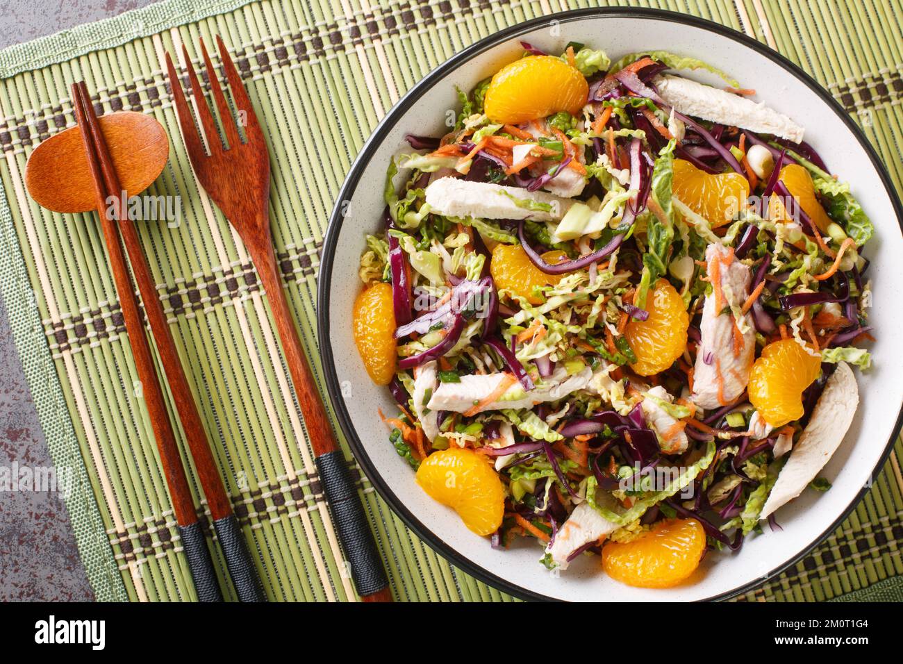 Chinesischer Hähnchensalat mit Mandarin, Kohl, Karotten, grünen Zwiebeln und Hähnchen mit asiatischem Dressing aus nächster Nähe in der Schüssel auf dem Tisch. Horizontal Stockfoto