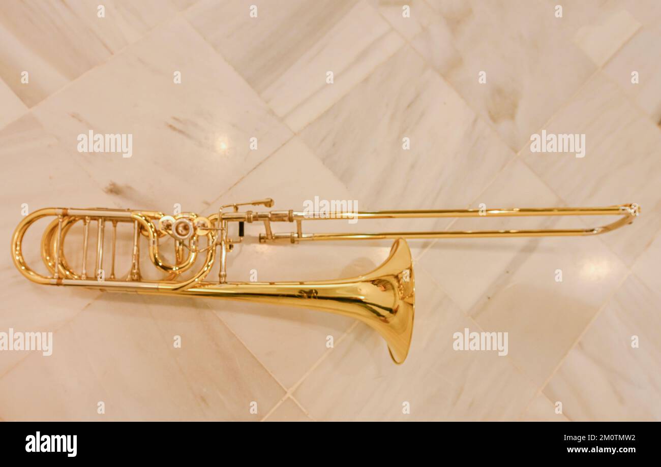Trombone, ein Luftmusikinstrument, das auf dem Marmorboden ruht. Stockfoto
