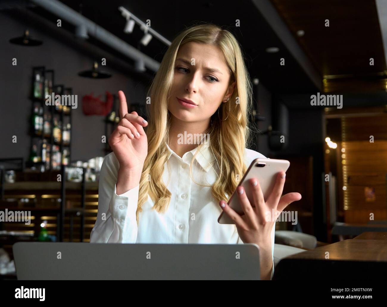 Verärgerte Geschäftsfrau, die telefoniert, auf den Laptop-Bildschirm schaut, junge Frau, die sich mit einem Kunden streitet, unangenehme Gespräche führt, sich in der Hand hält Stockfoto