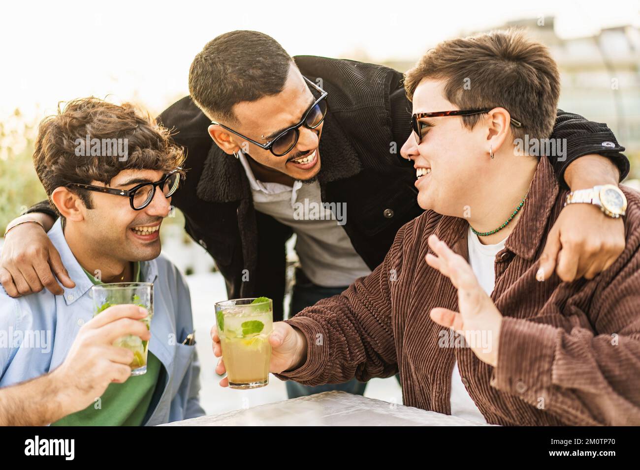 Eine vielfältige Gruppe von Freunden, die Spaß beim Trinken von Mojito-Cocktails haben und sich im Pub im Freien treffen - Integration, Vielfalt und Menschenleben Stockfoto