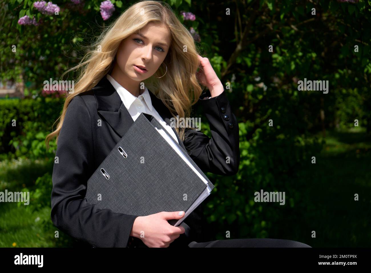 Hübsches blondes Mädchen, das Dokumente in der Hand hält und sich auf die Präsentation in der Technologiefirma vorbereitet. Stilvolle junge Frau im Business-Anzug. Stockfoto