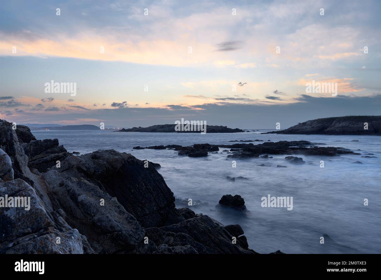 Das Wasser des Strands ist von schwarzen Felsen umgeben Stockfoto