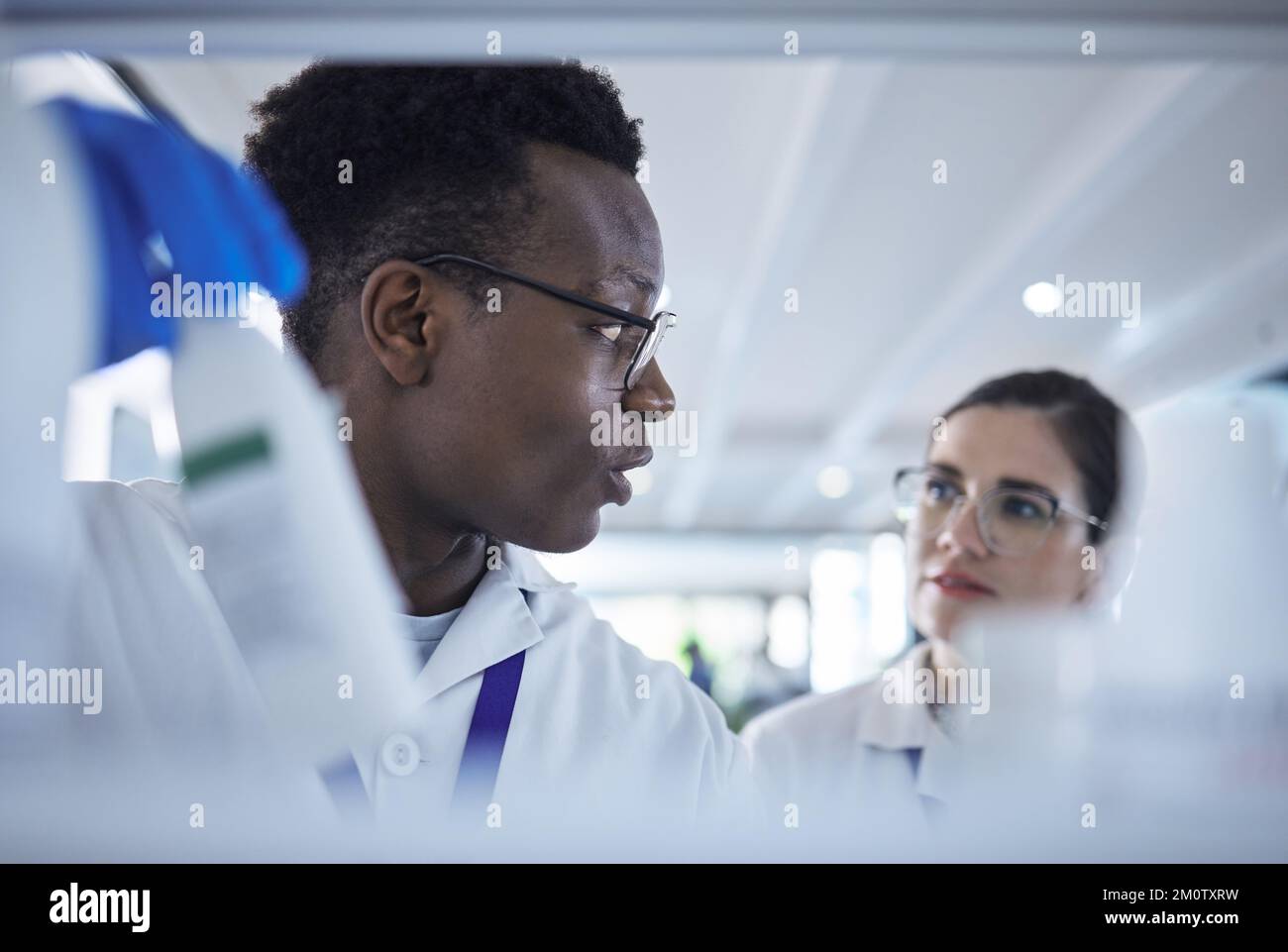 Junge afroamerikanische Wissenschaftlerin prüft Proben mit einer Kollegin.zwei Mediziner arbeiten gemeinsam an Experimenten im Labor Stockfoto