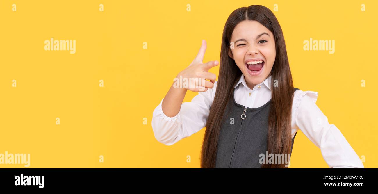 Blinzelndes Mädchen im Schulalter glückliches Lächeln Zeigen Fingergewehr Hand-Geste. Kindergesicht, horizontales Poster, isoliertes Porträt eines Teenagers, Banner Stockfoto